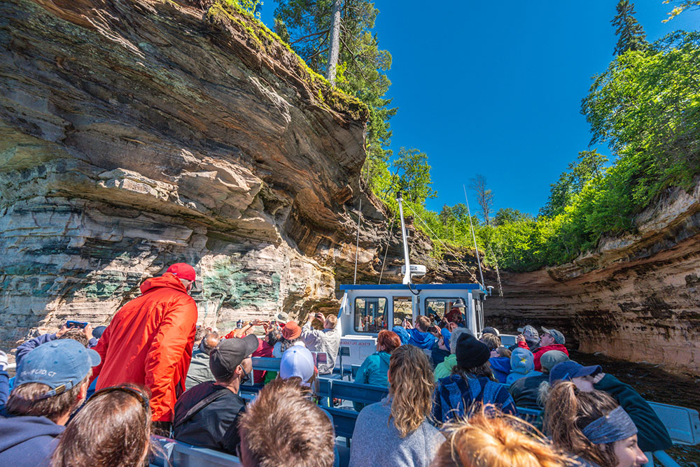 Passengers aboard a Pictured Rocks Cruises tour explore a cave. Photo credit: Tim Trombley