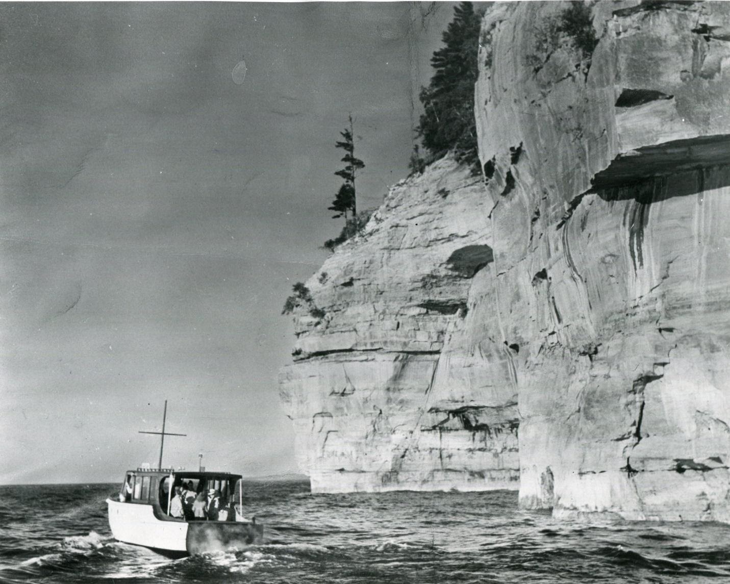 A tour boat cruises by the Pictured Rocks cliffs. PC: the Alger County Historical Society.