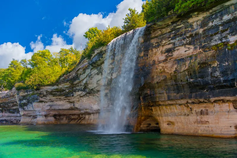 Spray Falls, Pictured Rocks: See the stunning waterfall's white spray against the cliffs as it plunges 70 feet into Lake Superior, a key attraction on our scenic boat tours.