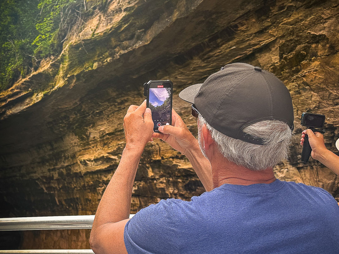 passenger photographing Chapel Cove on an afternoon Pictured Rocks boat tour