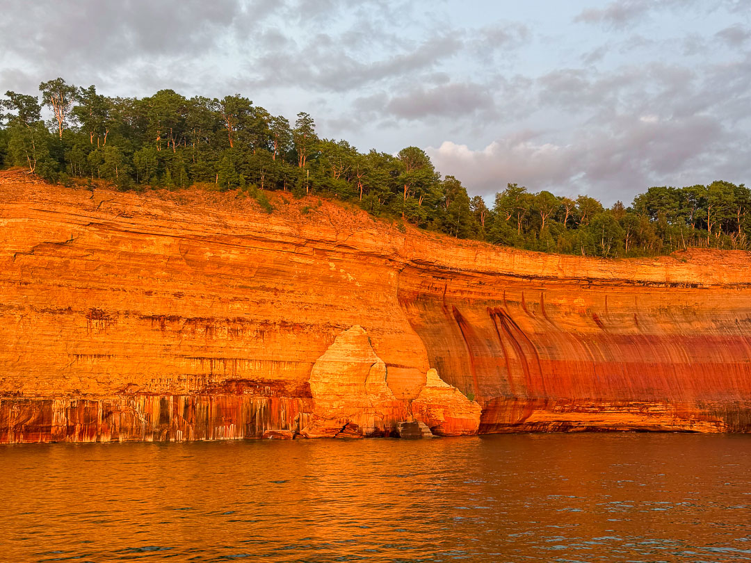 golden sunset light on the Pictured Rocks cliffs seen from a Pictured Rocks sunset cruise